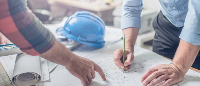 Hands of an architect and an engineer pointing at the architectural plan. they have a coordination meeting to make sure everything works